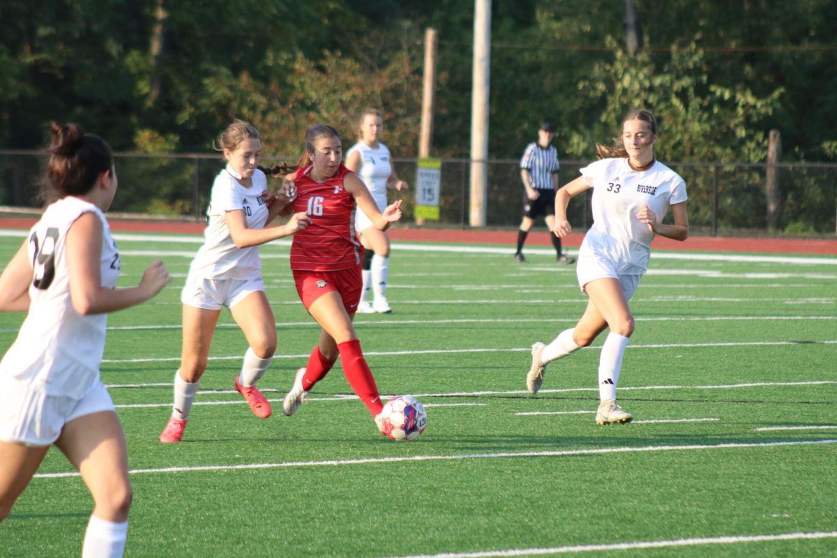 Strong shielding: Protecting the ball from the defender, Olivia Henderson (12) dribbles down the field. Maintaining possession is a key aspect of soccer because it means the team has a better chance of scoring.