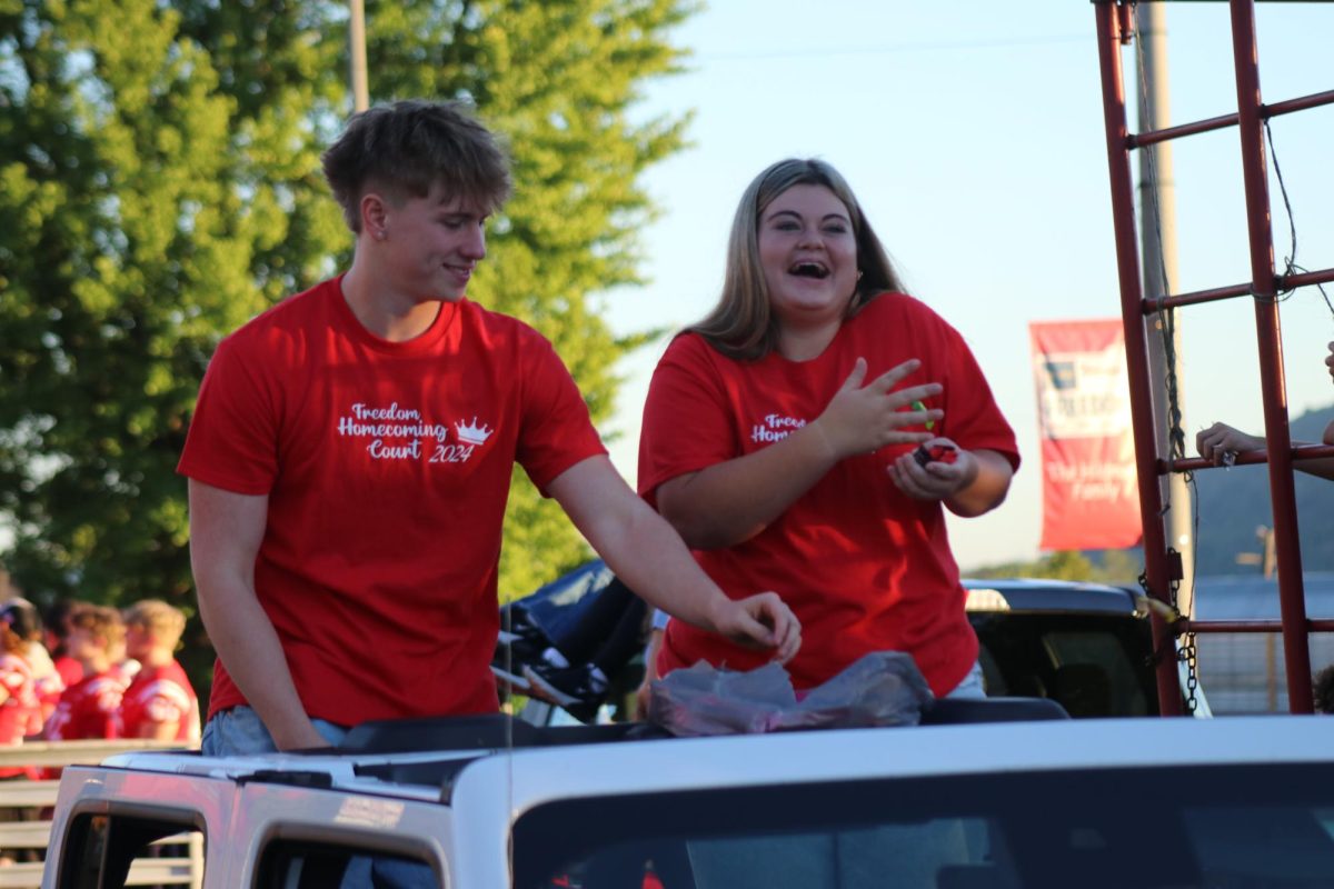 Life is a parade: Adam Rhoades (12) and Annabelle Komlos (12) smile as they throw candy to the crowd during the Homecoming Parade on Oct. 3. The parade was held on Third Avenue in Freedom.