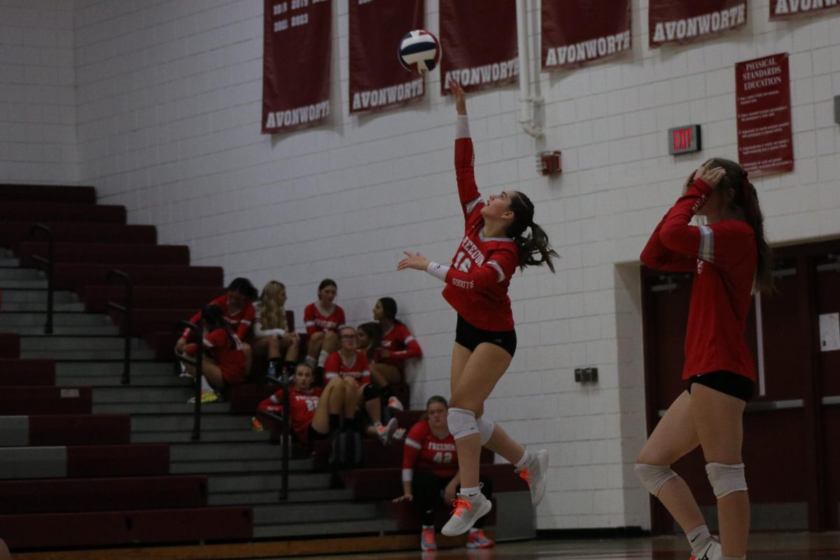 Super-serve: In the air, Riley Beegle (11) swings at the ball to serve it to the other team in hopes of scoring an ace serve. Beegle is the only one on the team who jump-serves during games.
