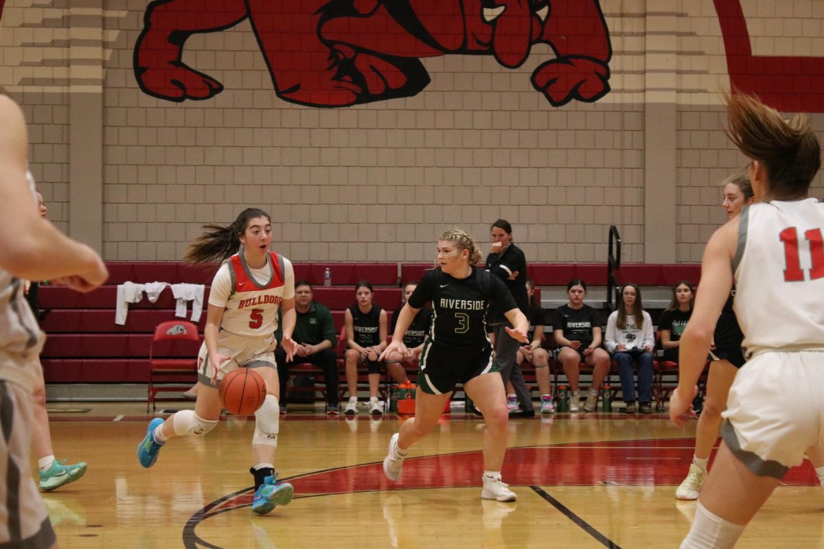 Basketball basics: Dribbling around the three-point line, Olivia Henderson (12) looks up to see the location of her teammates. Being able to look up while dribbling is vital to the success of the team because it allows them to prepare for their next pass, or prepare for a shot attempt.