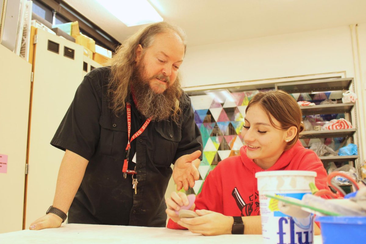 Helping hand: Looking down, Mr. Jim Gregg assists Harmony Martin (12) with her ceramics project. Many students go to the art room during PLT to get guidance from Gregg.