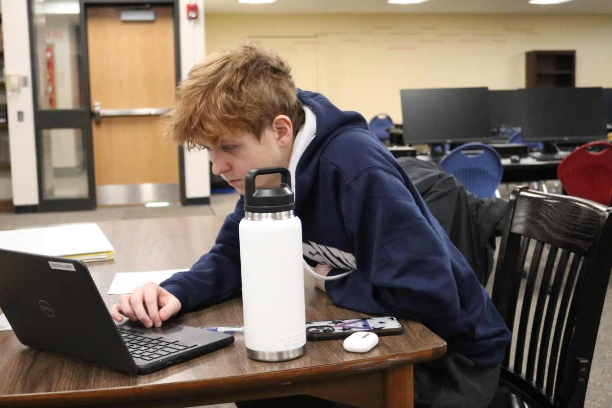 Inspiring students: Reading over an assignment, Colton Blank (11), stays focused as he helps tutor fellow students. The new NHS tutoring system is now available to students during every PLT.