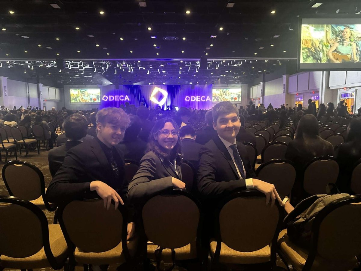 Medaled to the max: Sitting side by side, Colton Blank (11), Calla Reynolds (11) and Christopher Denkovich (12) wait as other attendees flow into the room. The state competition hosted over 7,000 competitors. 